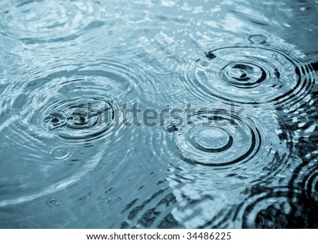 Rain drops rippling in a puddle with blue sky reflection Royalty-Free Stock Photo #34486225