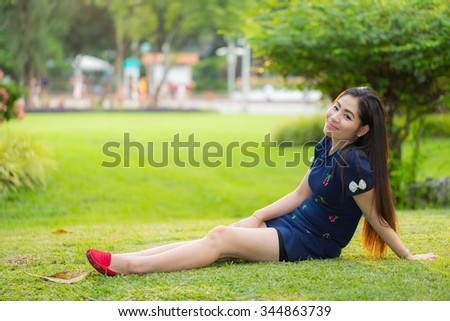 Happy Beautiful smiling young woman long hair sitting on green grass in the summer park  with Morning light