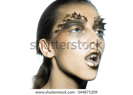 Closeup portrait of one beautiful wild young woman with bright golden animal monkey makeup with thorns on face in studio on white background, horizontal picture