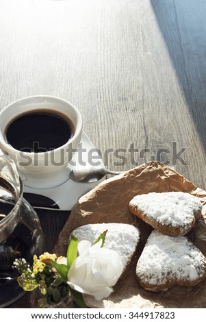 Heart shaped cookies (powdered sugar), cup of coffee, decoration on old wooden table. sunny morning.  Christmas breakfast or Valentine's Day Breakfast. Toned image