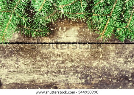 Branches of a Christmas tree on old boards. Christmas background. New Year background. Xmas background. Toned image. Falling Snow .