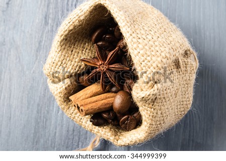 Coffee beans, star anise and cinnamon in bag on gray wooden table