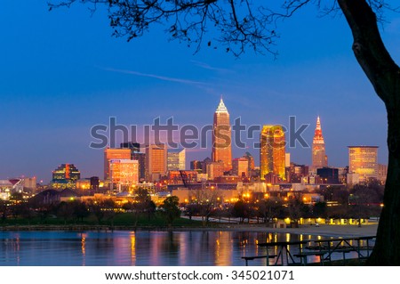 Downtown Cleveland, Ohio, glows in setting sunlight as the full moon prepares to rise under the pink clouds at center left