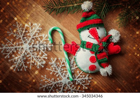 Christmas snowman felt in knit cap, scarf among snowflakes.