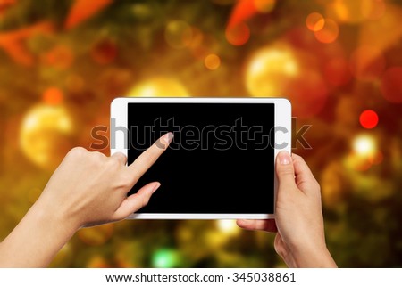 Woman using digital tablet PC against Christmas or New Year tree background with copy space. 