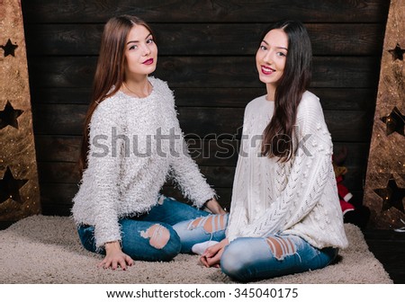 Indoor lifestyle portrait of two pretty young funny girls friends hugs smiling and having fun