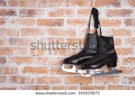 Old Black Figure Ice Skates Hanging On A Brick Wall 
