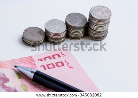 Coins setup in line graph put beside banknote. Put a pen on money, financial accounting concept.