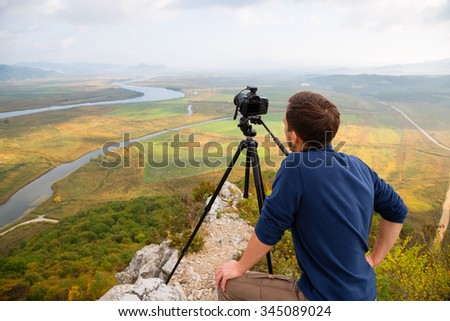 Photographer on top of a mountain landscape on the camera shoots.