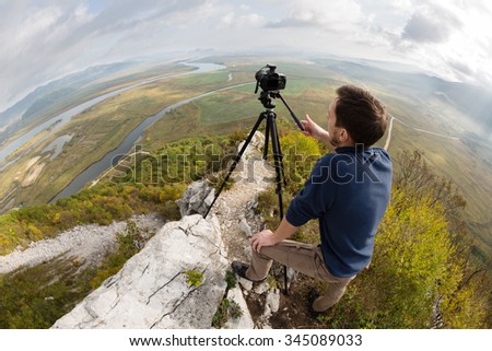 Photographer on top of the mountain takes a neighborhood on the camera. Taken with a fisheye lens.
