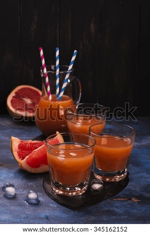 Fresh pomelo juice with ice over dark wooden background. Selective focus