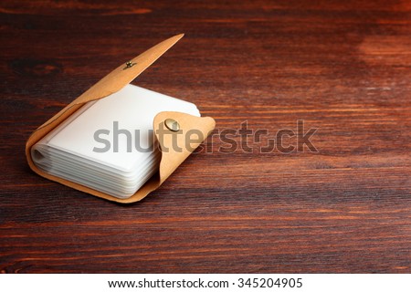 Outdoor business card holder, back cover made of natural material, lying on brown wooden Desk.