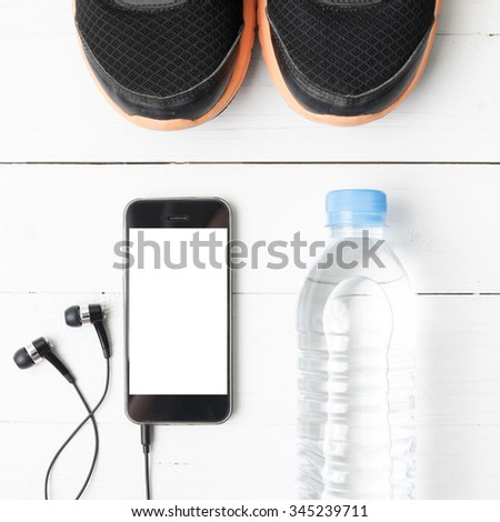 fitness equipment : running shoes,drinking water and phone on white wood table