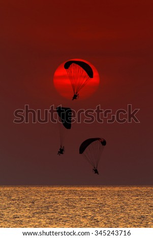 Paramotor flying on the sky in big sun at sunset