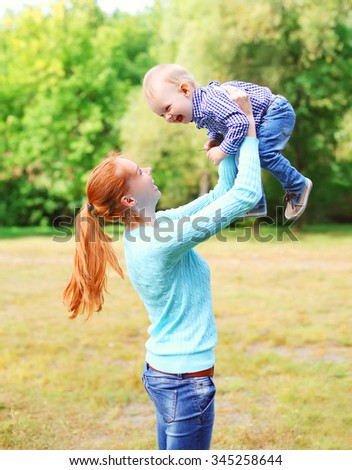 Happy smiling mother with son child having fun outdoors in park
