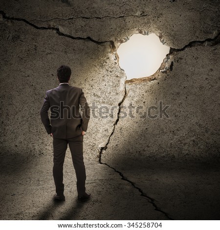 businessman standing and looking to light at the end of the tunnel