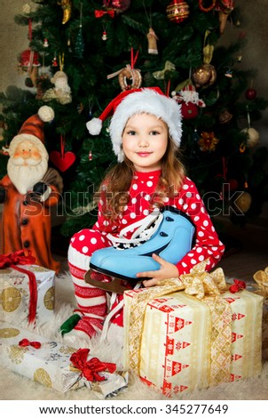 Beautiful girl in pajamas and cap is waiting Christmas and New year celebration front of X-mas tree. Old texture.