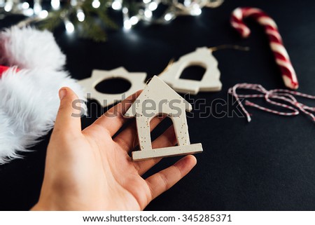 cute little kid hand and beautiful natural christmas toys and silver garland on black background
