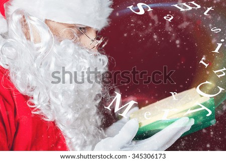 Santa Claus reading a book with Christmas fairy tale. Mature man blowing on the letters of Merry Christmas that fly with magical glitter and stardust. 