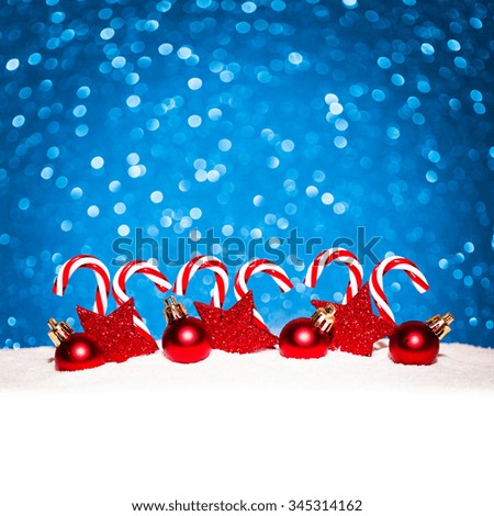 christmas red balls and candy in snow on blue glitter background. studio shot