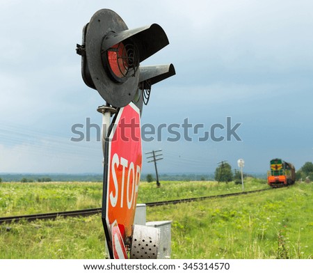Traffic lights and signs at the railroad crossing and the approaching train (Ukraine).