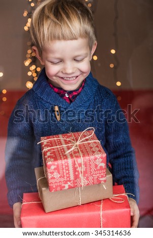 Smiling funny child holding Christmas gift in hand. Christmas concept. Birthday