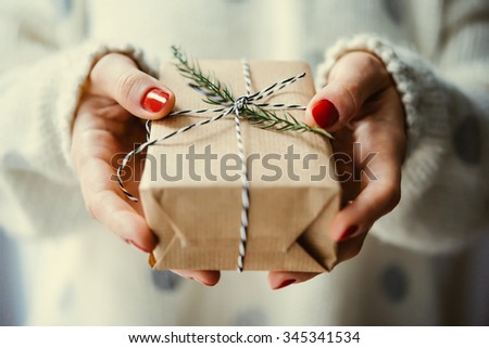 Woman's hands hold christmas or new year decorated gift box. Toned picture