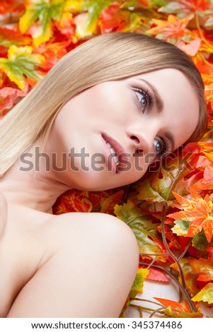 Beautiful young woman lying on autumn leafs