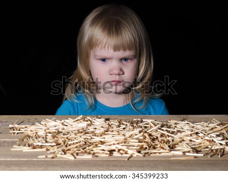 Little child and Lucifer match. Lucifer match are not toys for children. A lot of matches on the table. Child scared. Black background. Dangerous Games with fire Royalty-Free Stock Photo #345399233