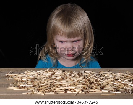 Little child and Lucifer match. Lucifer match are not toys for children. A lot of matches on the table. Child scared. Black background. Dangerous Games with fire Royalty-Free Stock Photo #345399245