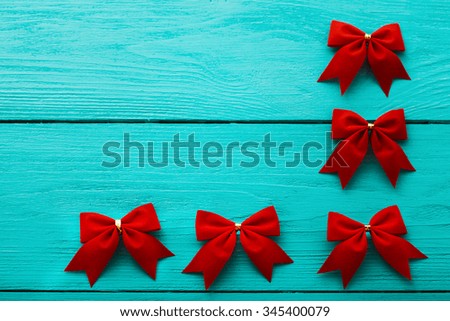 Frame of red bows on blue wooden background with copy space. Top view