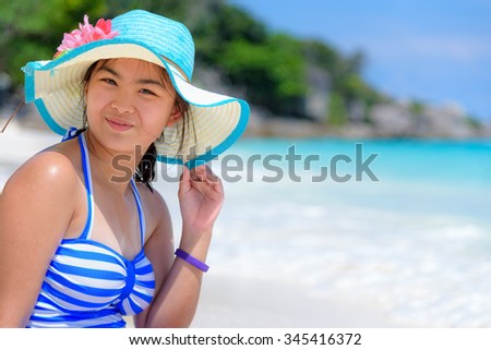 Girl in a blue swimwear sitting a happy on the beach with the sea as background during summer at Koh Miang Island, Mu Ko Similan National Park, Phang Nga province, Thailand