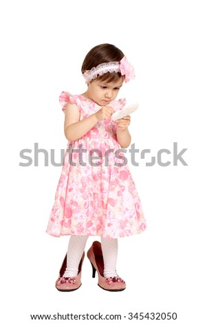 Beautiful little girl in a pink dress and big shoes stands on a white background