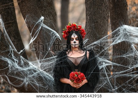 Beautiful woman in makeup traditional Mexican Calavera skull Katrina in the autumn forest, in a wreath of red flowers