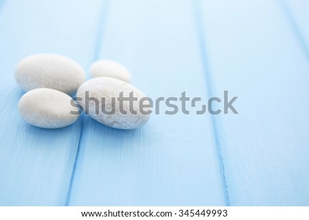 Stones isolated on wood background. Pile of white stones on a blue smooth wooden table