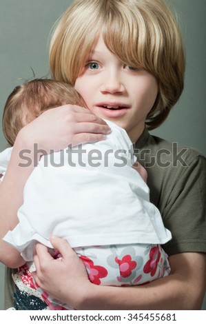 Boy lovingly holding his new born baby sister