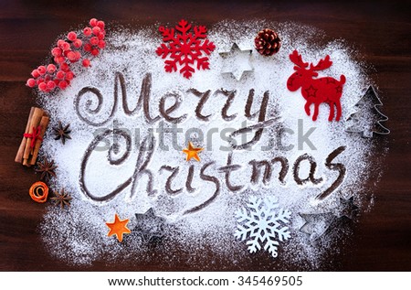 Merry Christmas text made with flour with decorations on cutting board