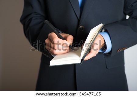 Hand writes in a notebook. advertising or business concept, isolated on a gray background.