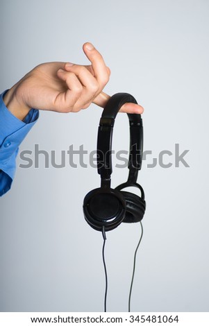 man's hand holding stylish headphones. advertising concept, isolated on a gray background.