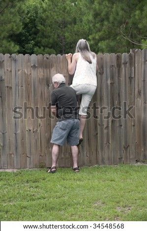 Her husband helps her peek over the fence to see what the neighbors are up to! Royalty-Free Stock Photo #34548568