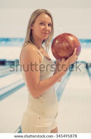 Pretty woman holding ball in bowling club.