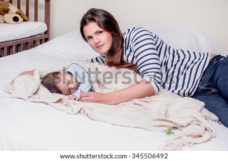 Closeup of beautiful loving mother with small tiny cute male lovely baby indoor in bed with white linen lying close to each other, horizontal picture