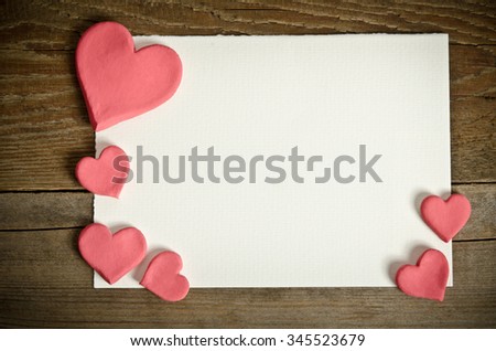 white paper with small pink hearts lying on a wooden background