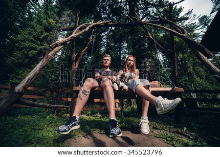 beautiful couple together with a dog resting on a swing. Picture taken from below