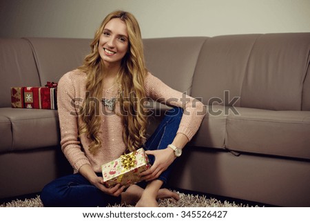 Beautiful blond woman holds a gift on christmas day. Color effects and custom white balance are used on this picture.
