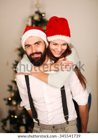 Joyful couple in red hats on the background of the Christmas tree