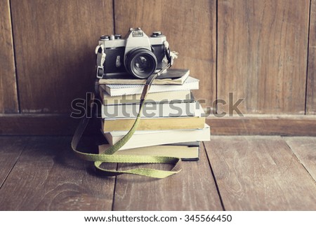 Old style camera on pile of books on wooden floor