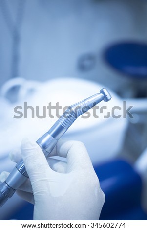 Dental instrumentation dentist drill tooth dental cleaning tool in the hand of dentist in dentists surgery clinic artistic color photo with shallow depth of focus.