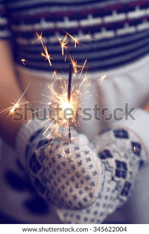 Woman holding a Christmas Decorations. Christmas Background. Woman holding a sparkler. Knitted mittens. Happy Holidays. Knitted dress. Toned image.