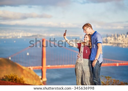 Romantic loving couple making selfie in San Francisco, California, USA. Golden gate bridge in the background